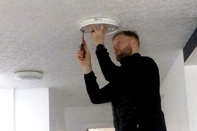 KF Watson engineer working from a ladder installing ceiling lighting in an office